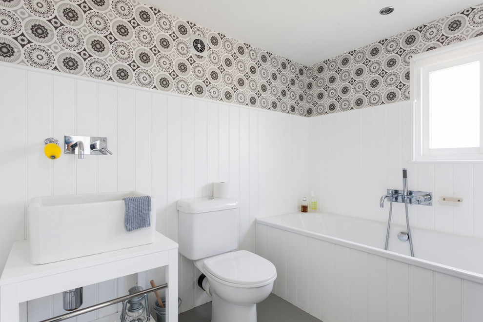 Nordisches Badezimmer mit Aufsatzwaschbecken, weißen Schränken, Badewanne in Nische, Wandtoilette mit Spülkasten und bunten Wänden in London