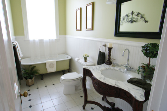 На фото: ванная комната в викторианском стиле с ванной на ножках, зелеными стенами, полом из керамической плитки, раковиной с пьедесталом, мраморной столешницей, белым полом и разноцветной столешницей