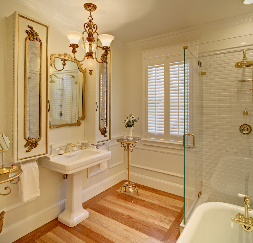 Inspiration for a medium sized traditional bathroom in New York with a pedestal sink, a claw-foot bath, a corner shower, white tiles, white walls and light hardwood flooring.