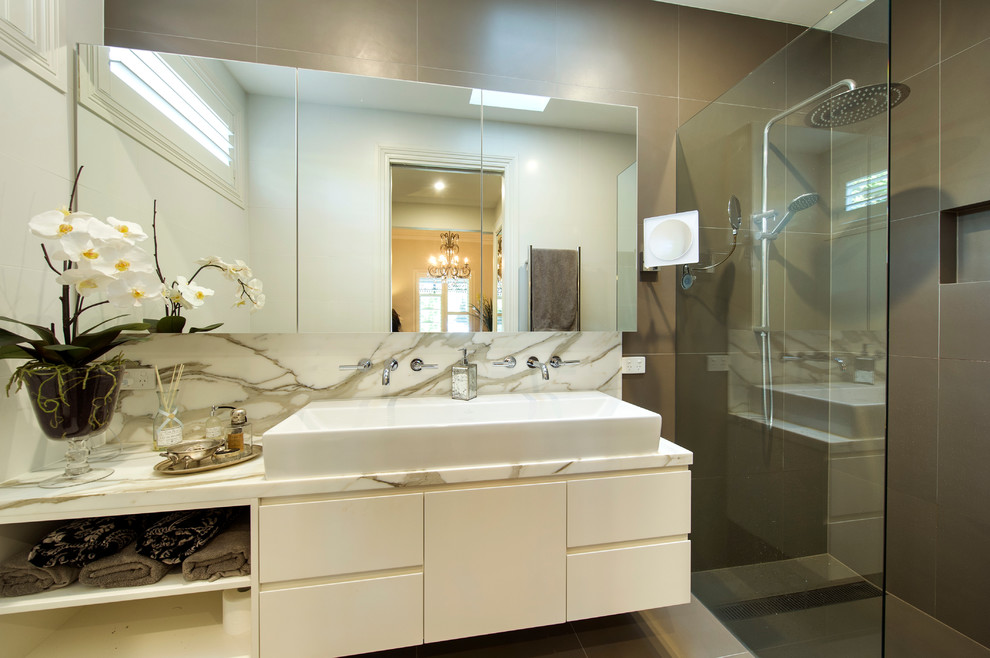 На фото: главная ванная комната среднего размера в викторианском стиле с настольной раковиной, белыми фасадами, мраморной столешницей, двойным душем, коричневой плиткой, керамической плиткой, белыми стенами и полом из керамической плитки с