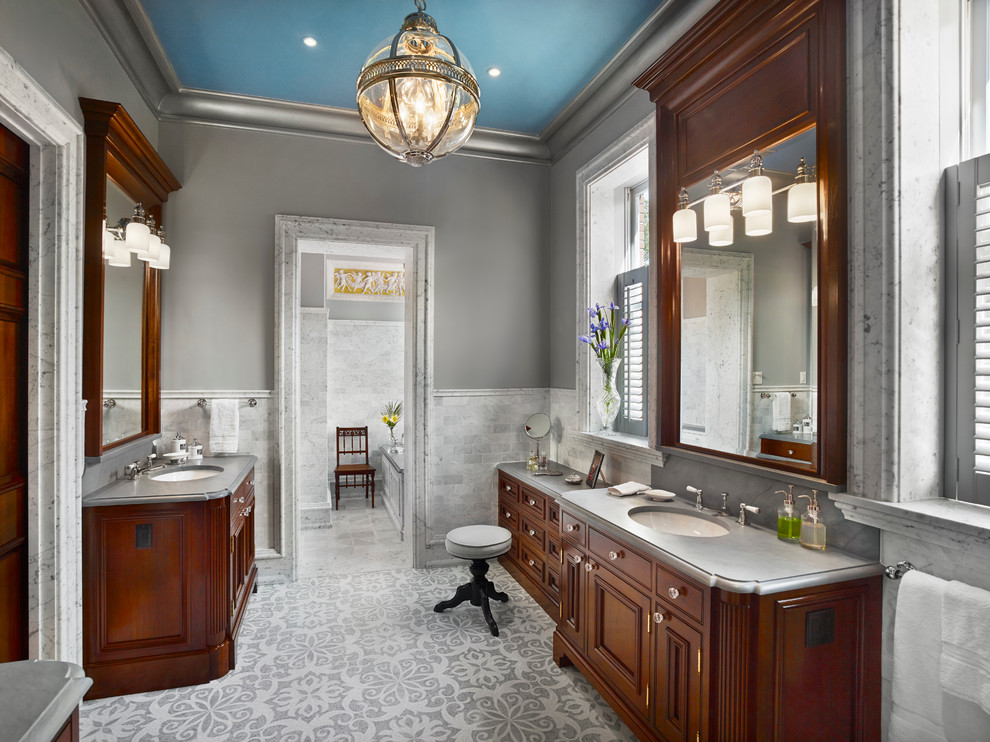 На фото: большая главная ванная комната в викторианском стиле с фасадами с выступающей филенкой, темными деревянными фасадами, разноцветной плиткой, серыми стенами, мраморным полом, врезной раковиной и мраморной столешницей