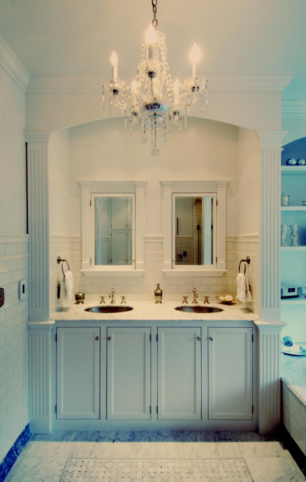 Cette photo montre une salle de bain principale victorienne de taille moyenne avec un placard à porte affleurante, des portes de placard blanches, une baignoire encastrée, un carrelage blanc, un carrelage métro, un mur blanc, un sol en marbre, un lavabo encastré, un plan de toilette en granite, un sol blanc et un plan de toilette blanc.