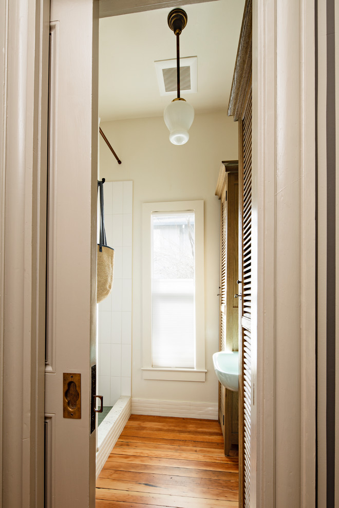 Идея дизайна: маленькая ванная комната в викторианском стиле с душевой кабиной, фасадами с филенкой типа жалюзи, фасадами цвета дерева среднего тона, душем в нише, белой плиткой, керамической плиткой, белыми стенами, паркетным полом среднего тона, раковиной с пьедесталом, коричневым полом и шторкой для ванной для на участке и в саду