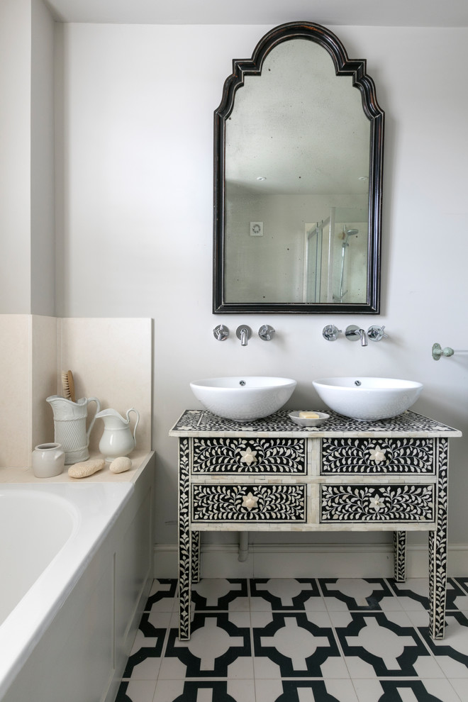 Imagen de cuarto de baño mediterráneo pequeño con paredes blancas, lavabo sobreencimera, suelo multicolor, encimeras multicolor, puertas de armario negras, bañera encastrada y armarios con paneles lisos
