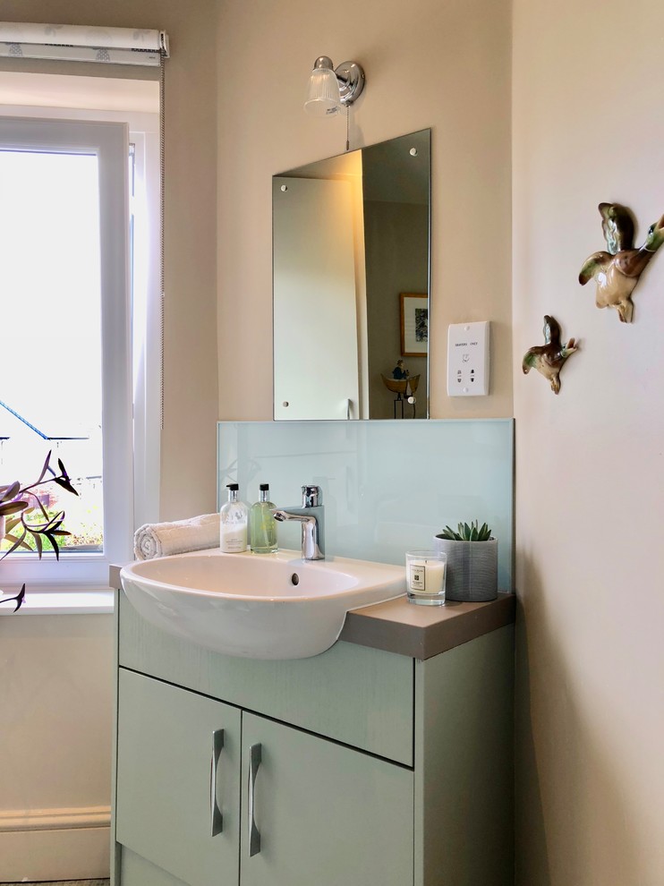На фото: маленькая ванная комната в классическом стиле с плоскими фасадами, зелеными фасадами, открытым душем, унитазом-моноблоком, зеленой плиткой, плиткой из листового стекла, бежевыми стенами, полом из винила, душевой кабиной, накладной раковиной, столешницей из ламината, зеленым полом, душем с раздвижными дверями и серой столешницей для на участке и в саду с