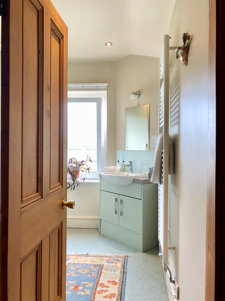 Пример оригинального дизайна: маленькая ванная комната в классическом стиле с плоскими фасадами, зелеными фасадами, открытым душем, унитазом-моноблоком, зеленой плиткой, плиткой из листового стекла, бежевыми стенами, полом из винила, душевой кабиной, накладной раковиной, столешницей из ламината, зеленым полом, душем с раздвижными дверями и серой столешницей для на участке и в саду