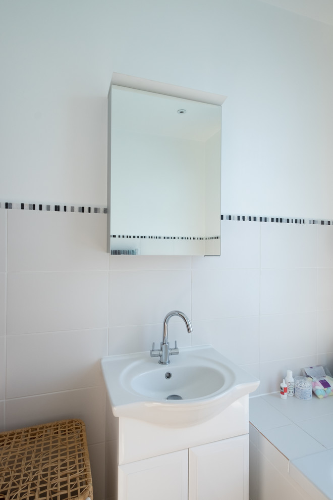 Imagen de cuarto de baño infantil contemporáneo pequeño con sanitario de pared, baldosas y/o azulejos blancos, paredes blancas, suelo de piedra caliza y suelo gris