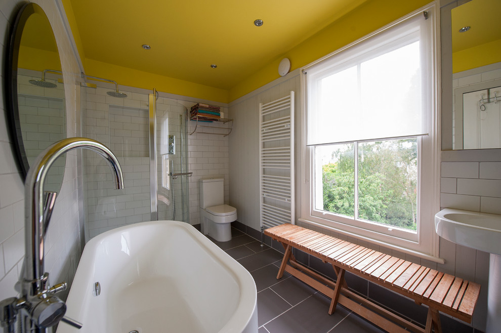 Пример оригинального дизайна: детская ванная комната в стиле фьюжн с раковиной с пьедесталом, светлыми деревянными фасадами, отдельно стоящей ванной, угловым душем, унитазом-моноблоком, белой плиткой, керамической плиткой, белыми стенами и полом из керамической плитки