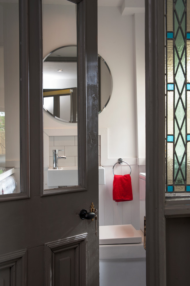 Imagen de cuarto de baño ecléctico con lavabo suspendido, sanitario de una pieza, baldosas y/o azulejos blancos, paredes blancas y suelo de baldosas de cerámica