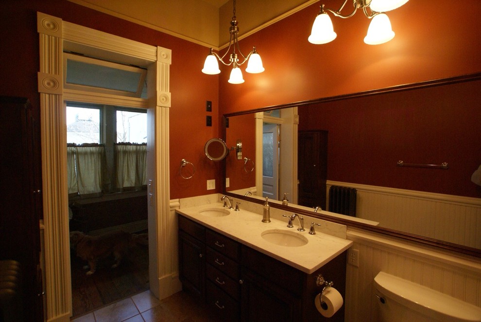 This is an example of a large classic family bathroom in St Louis with a submerged sink, freestanding cabinets, dark wood cabinets, marble worktops, an alcove bath, a shower/bath combination, a two-piece toilet, beige tiles, ceramic tiles, multi-coloured walls and ceramic flooring.