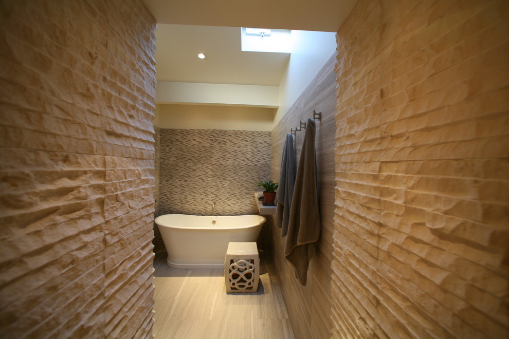 Immagine di una grande stanza da bagno padronale design con top in cemento, vasca freestanding, piastrelle in pietra, pavimento in travertino, doccia aperta e pareti beige