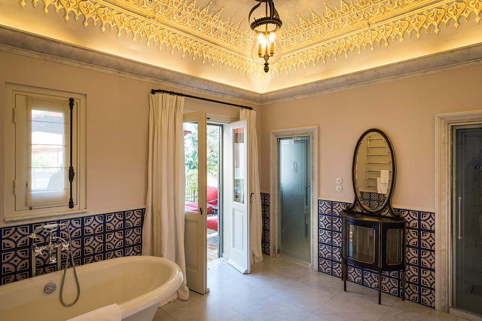 Medelhavsstil inredning av ett badrum, med ett badkar med tassar, en dusch i en alkov och flerfärgade väggar