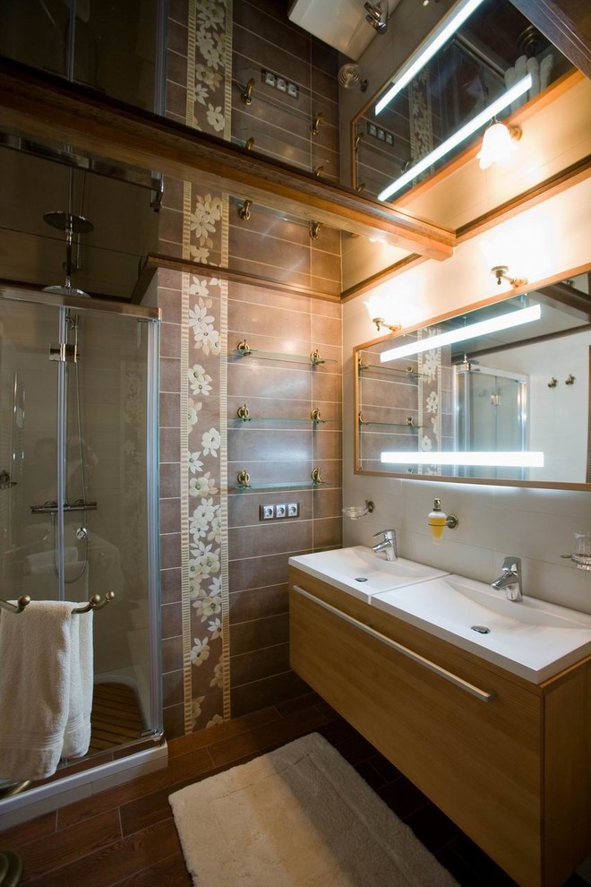 Inredning av ett klassiskt mellanstort vit vitt en-suite badrum, med ett avlångt handfat, släta luckor, skåp i mellenmörkt trä, en dusch i en alkov, brun kakel, mörkt trägolv, bruna väggar, en toalettstol med separat cisternkåpa, bänkskiva i akrylsten, brunt golv och dusch med skjutdörr