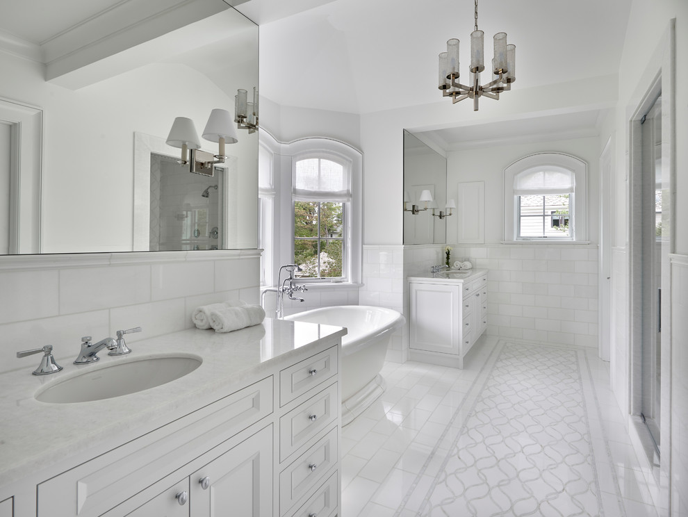 Idéer för medelhavsstil vitt en-suite badrum, med vita skåp, ett fristående badkar, vit kakel, vita väggar, marmorgolv, vitt golv, dusch med gångjärnsdörr, luckor med infälld panel, en dusch i en alkov, tunnelbanekakel och ett undermonterad handfat