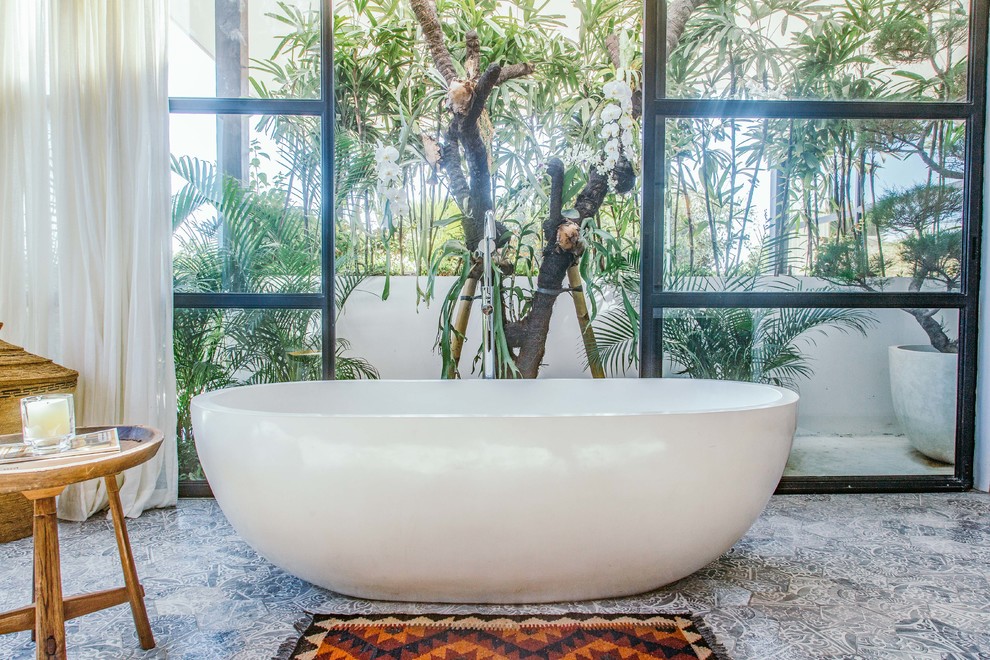 Idee per una stanza da bagno tropicale con vasca freestanding e pavimento grigio