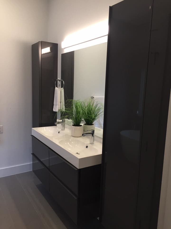 Aménagement d'une salle de bain principale moderne de taille moyenne avec un placard à porte plane, des portes de placard noires, un mur blanc, parquet clair, un lavabo intégré, un plan de toilette en quartz modifié et un sol marron.