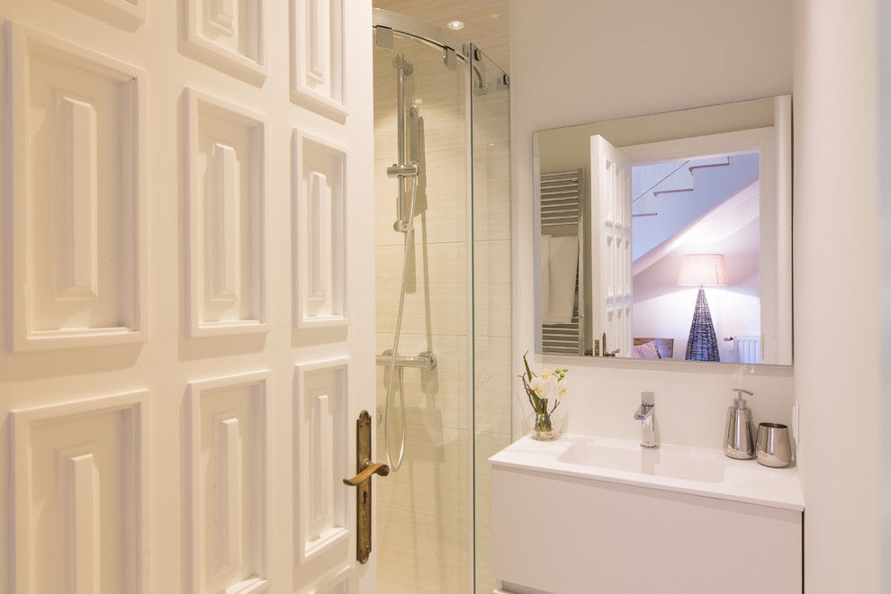 Modelo de cuarto de baño clásico renovado de tamaño medio con armarios con paneles lisos, puertas de armario blancas, ducha empotrada, paredes blancas, aseo y ducha y lavabo integrado