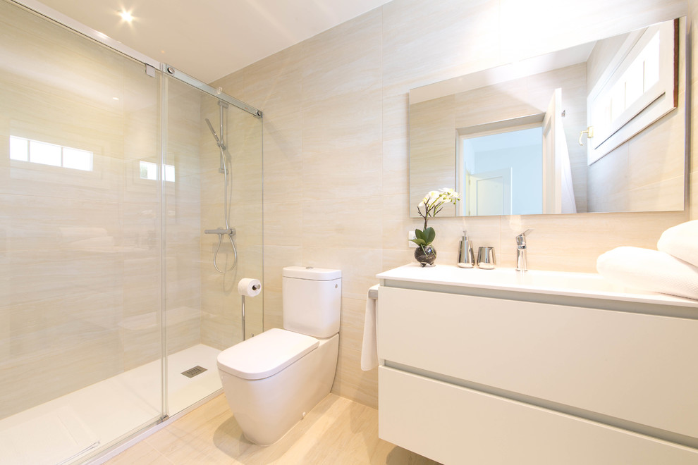 Imagen de cuarto de baño nórdico de tamaño medio con armarios con paneles lisos, puertas de armario blancas, ducha empotrada, sanitario de dos piezas, paredes beige, aseo y ducha y lavabo integrado