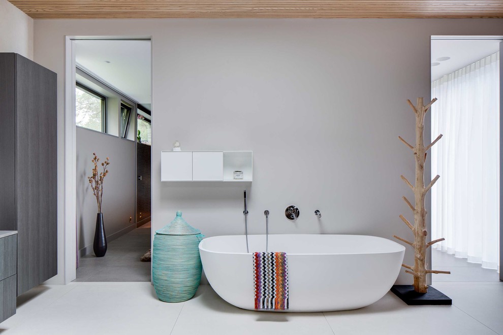 Minimalistisk inredning av ett mellanstort en-suite badrum, med släta luckor, grå skåp, ett fristående badkar och grå väggar