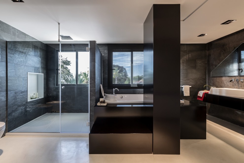 Réalisation d'une grande salle de bain principale design avec une baignoire posée, un mur noir, sol en béton ciré, une vasque, un combiné douche/baignoire et meuble-lavabo encastré.