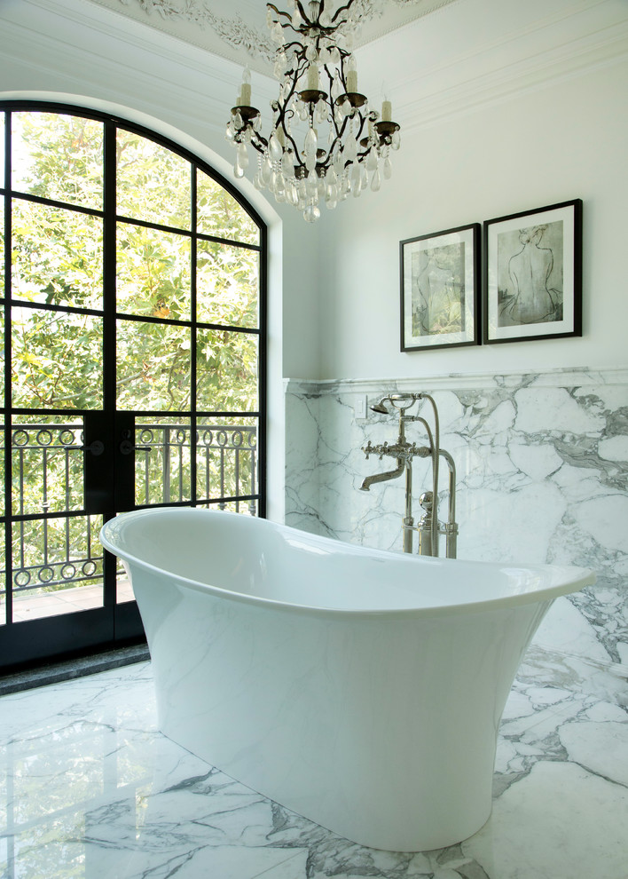 Inredning av ett medelhavsstil badrum, med ett fristående badkar, vit kakel och marmorkakel