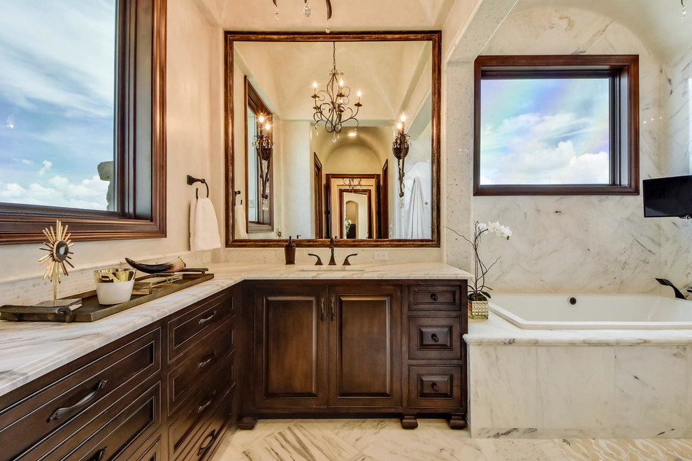 Example of a large tuscan master white tile and stone tile marble floor bathroom design in Austin with raised-panel cabinets, medium tone wood cabinets, a one-piece toilet, white walls, an undermount sink and marble countertops