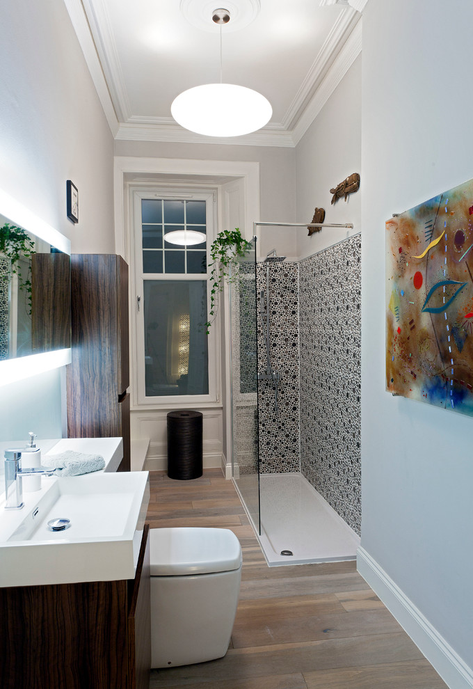 Kleines Modernes Badezimmer mit Wandtoilette mit Spülkasten, braunem Holzboden, flächenbündigen Schrankfronten, dunklen Holzschränken, Eckdusche, integriertem Waschbecken, grauer Wandfarbe und offener Dusche in Glasgow