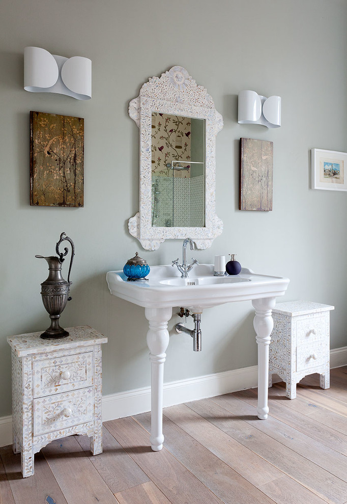 Foto på ett stort vintage badrum, med vita skåp, ett badkar med tassar, en toalettstol med separat cisternkåpa, grå väggar, mellanmörkt trägolv och ett konsol handfat