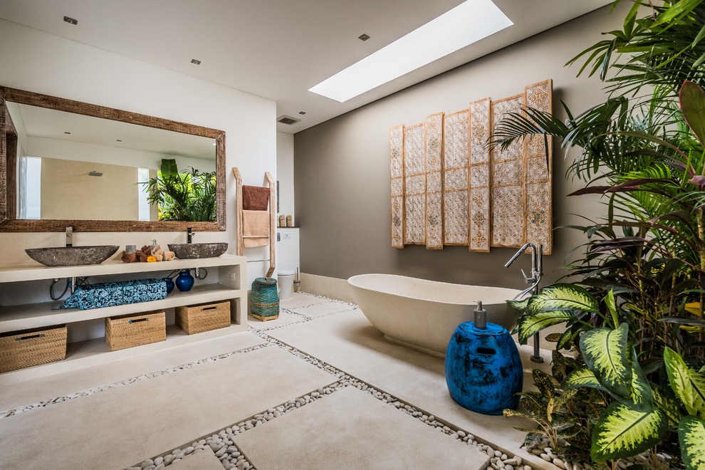 Idee per una stanza da bagno padronale tropicale con nessun'anta, ante beige, vasca freestanding, pareti grigie, pavimento in cemento, lavabo a bacinella, pavimento grigio e top beige