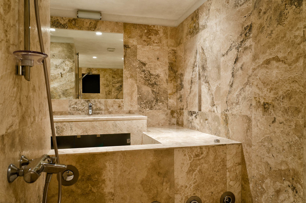 Immagine di una stanza da bagno tradizionale di medie dimensioni con lavabo integrato, vasca da incasso, vasca/doccia, piastrelle beige, piastrelle in pietra, pareti beige e pavimento in travertino