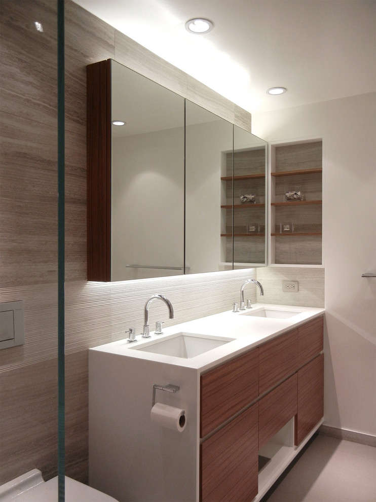 Example of a large trendy master concrete floor alcove shower design in New York with an undermount sink, medium tone wood cabinets, a wall-mount toilet, gray walls, flat-panel cabinets and solid surface countertops