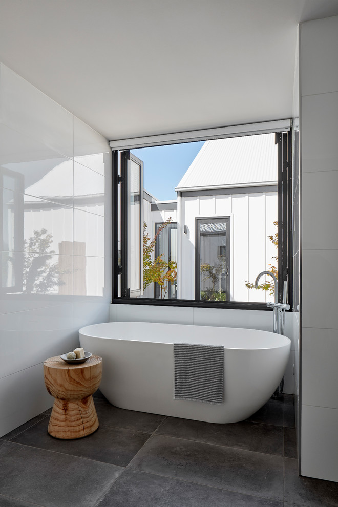 Exempel på ett mellanstort lantligt badrum, med ett fristående badkar, vit kakel, keramikplattor, klinkergolv i keramik och grått golv