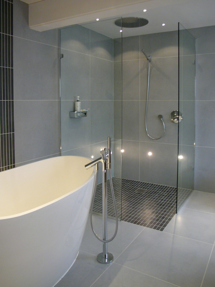 Idéer för mellanstora funkis en-suite badrum, med ett fristående badkar, en kantlös dusch, grå kakel, porslinskakel, grå väggar och klinkergolv i porslin