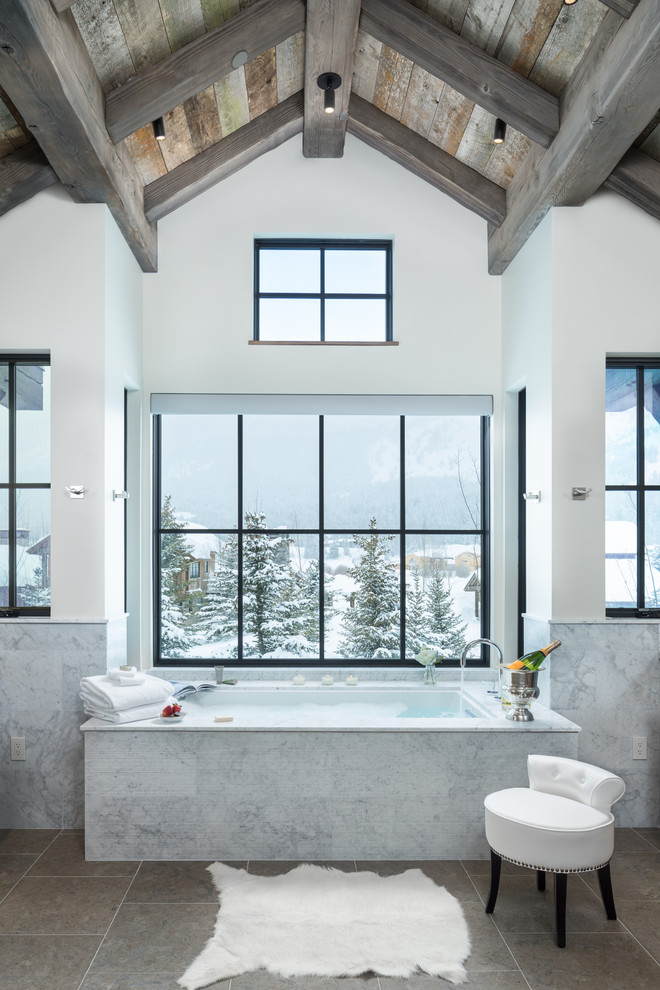 На фото: ванная комната в стиле рустика с светлыми деревянными фасадами, ванной в нише, серой плиткой, мраморной столешницей и серой столешницей с