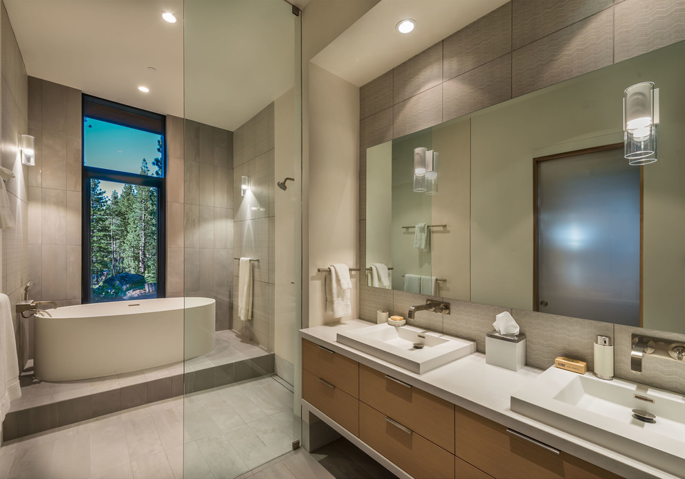 На фото: главная ванная комната в современном стиле с плоскими фасадами, светлыми деревянными фасадами, отдельно стоящей ванной, серой плиткой, серым полом и открытым душем с