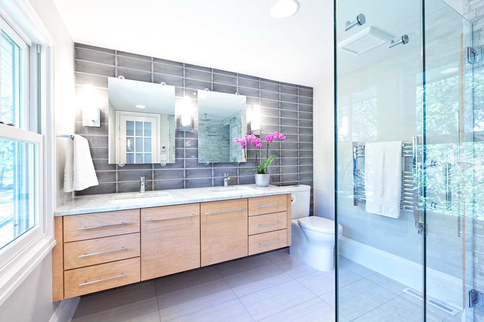 Свежая идея для дизайна: главная ванная комната среднего размера в современном стиле с плоскими фасадами, светлыми деревянными фасадами, душем в нише, унитазом-моноблоком, серой плиткой, керамической плиткой, серыми стенами, полом из керамогранита, врезной раковиной, мраморной столешницей, серым полом и душем с распашными дверями - отличное фото интерьера