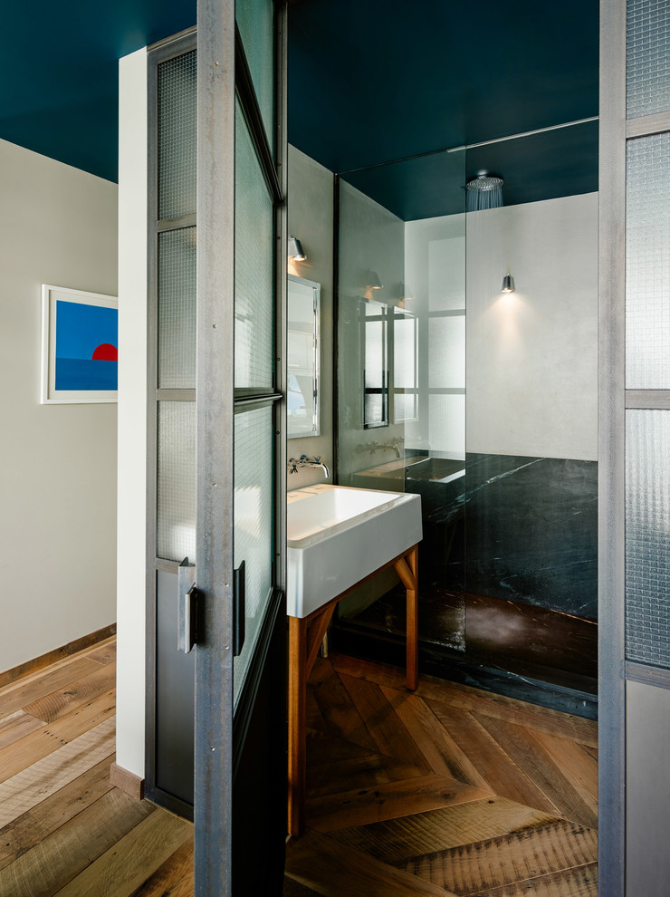 Kleines Modernes Badezimmer En Suite mit Waschtischkonsole, Eckdusche, Steinplatten, weißer Wandfarbe, braunem Holzboden und grauen Fliesen in New York