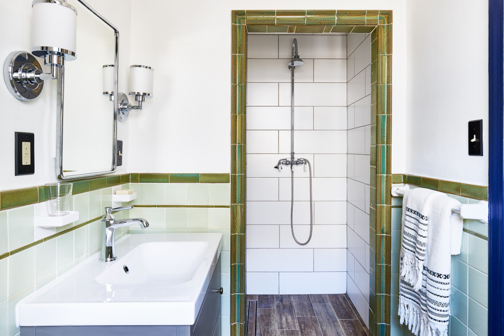 Пример оригинального дизайна: маленькая ванная комната в стиле фьюжн с серыми фасадами, душевой комнатой, зеленой плиткой, керамической плиткой, белыми стенами, полом из плитки под дерево, душевой кабиной, консольной раковиной, столешницей из искусственного камня, коричневым полом, открытым душем, белой столешницей, тумбой под одну раковину и напольной тумбой для на участке и в саду