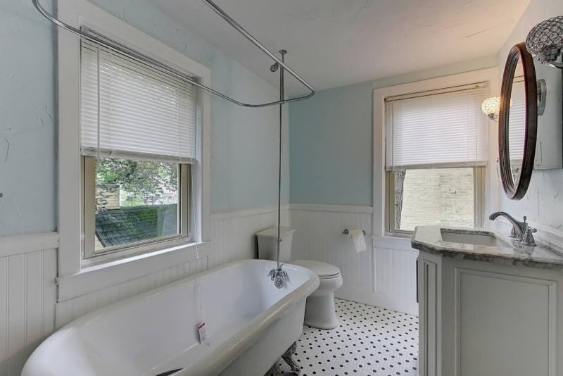 Claw-foot bathtub - mid-sized farmhouse ceramic tile ceramic tile claw-foot bathtub idea in Other with a drop-in sink, raised-panel cabinets, white cabinets, marble countertops, a two-piece toilet and blue walls