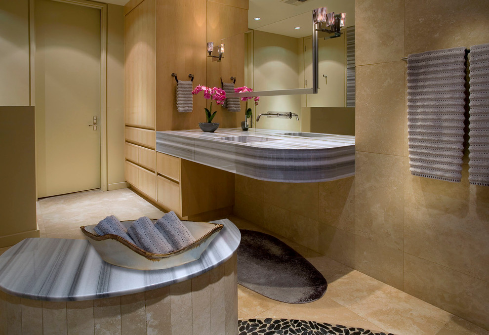 ロサンゼルスにあるトランジショナルスタイルのおしゃれな浴室 (一体型シンク、フラットパネル扉のキャビネット、淡色木目調キャビネット、大理石の洗面台、オープン型シャワー、ベージュのタイル、石タイル) の写真