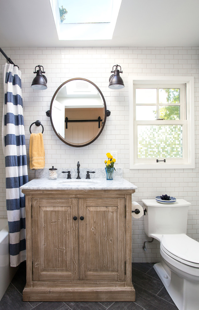 Beach style white tile and subway tile gray floor shower curtain photo in Seattle with raised-panel cabinets, medium tone wood cabinets, a one-piece toilet, white walls, an undermount sink and gray countertops