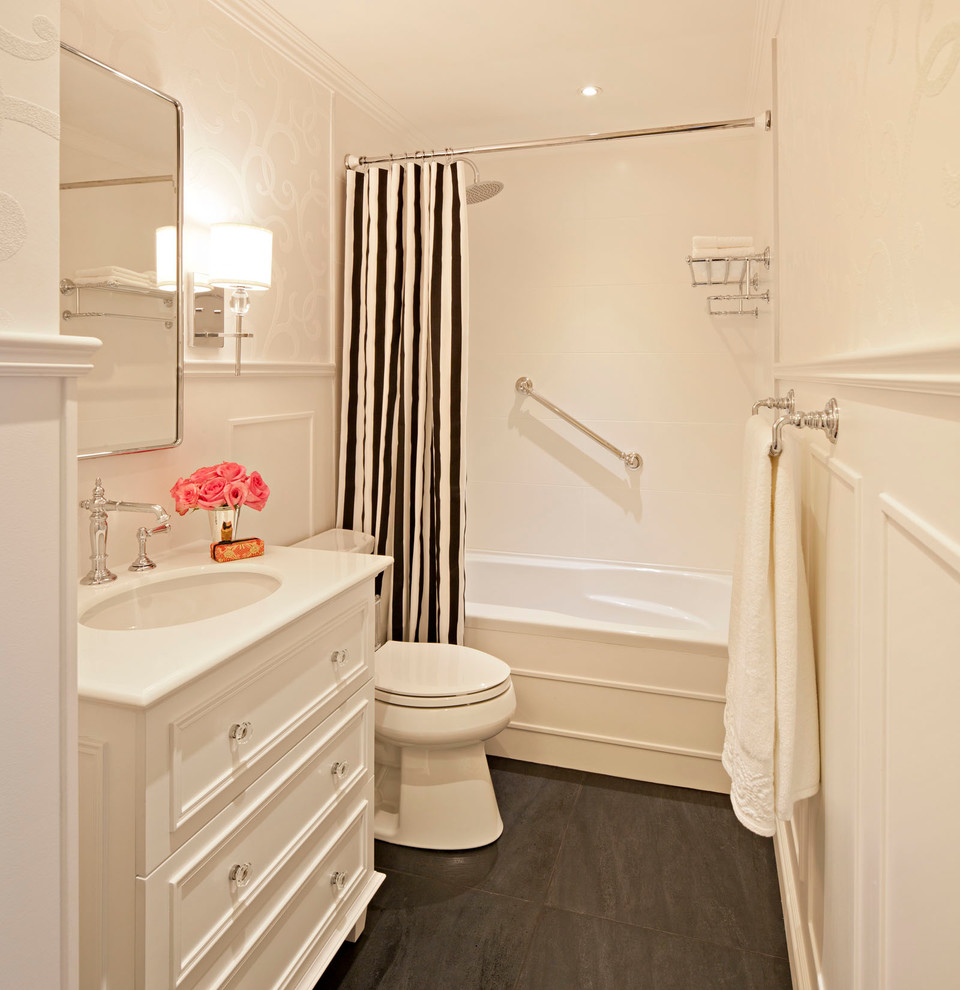 Bild på ett litet vintage en-suite badrum, med ett undermonterad handfat, vita skåp, bänkskiva i akrylsten, ett badkar i en alkov, en dusch i en alkov, en toalettstol med separat cisternkåpa, vit kakel, porslinskakel, vita väggar, skiffergolv och luckor med infälld panel