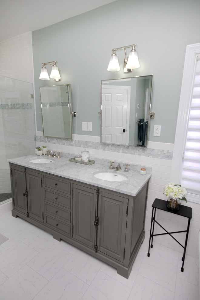 Cette image montre une salle de bain principale victorienne de taille moyenne avec un placard à porte affleurante, des portes de placard grises, une baignoire sur pieds, un carrelage blanc, un mur vert, un sol en marbre, un lavabo encastré et un plan de toilette en marbre.