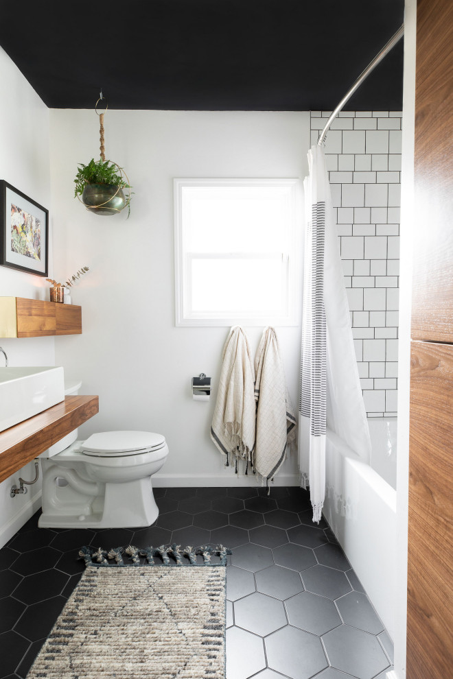 Réalisation d'une salle de bain design avec une baignoire en alcôve, un carrelage blanc, un mur blanc, une vasque, un plan de toilette en bois, un sol noir et un plan de toilette marron.