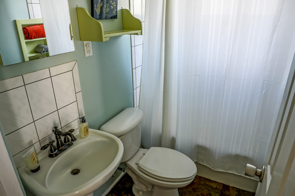 Amerikansk inredning av ett litet en-suite badrum, med en dusch/badkar-kombination, en toalettstol med separat cisternkåpa, vit kakel, keramikplattor, blå väggar och ett piedestal handfat