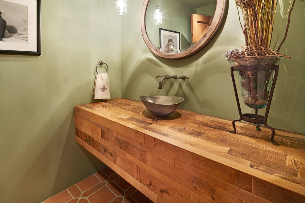 Modelo de cuarto de baño mediterráneo pequeño con paredes verdes, suelo de baldosas de terracota, aseo y ducha, encimera de madera y lavabo sobreencimera