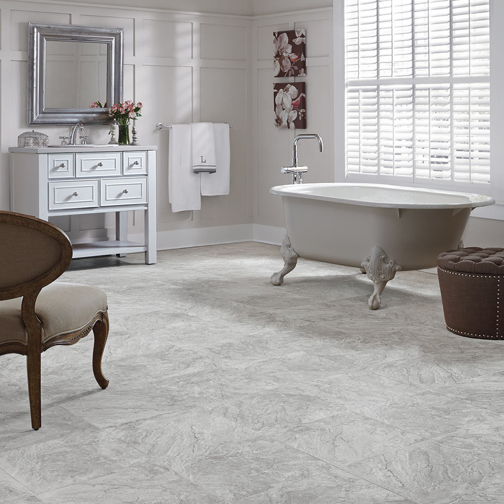 Cette photo montre une grande salle de bain principale tendance avec des portes de placard blanches, une baignoire sur pieds, un carrelage gris, des carreaux de porcelaine, un mur gris, un sol en carrelage de porcelaine, un placard à porte affleurante, un lavabo posé et un sol gris.