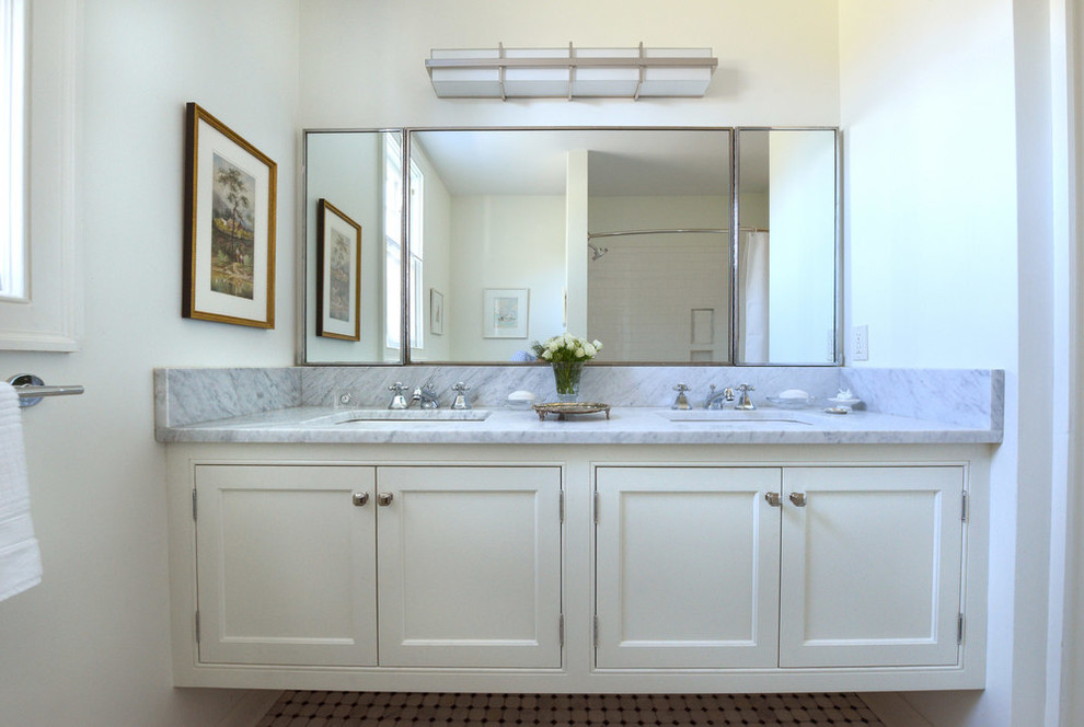 Inredning av ett klassiskt stort en-suite badrum, med luckor med profilerade fronter, vita skåp, ett badkar i en alkov, en dusch/badkar-kombination, en toalettstol med hel cisternkåpa, vit kakel, tunnelbanekakel, vita väggar, mosaikgolv, ett undermonterad handfat och marmorbänkskiva