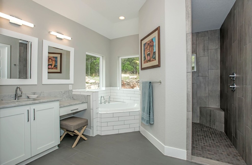 Large traditional ensuite bathroom in Austin with recessed-panel cabinets, white cabinets, a corner bath, a corner shower, white tiles, grey walls, a submerged sink and an open shower.