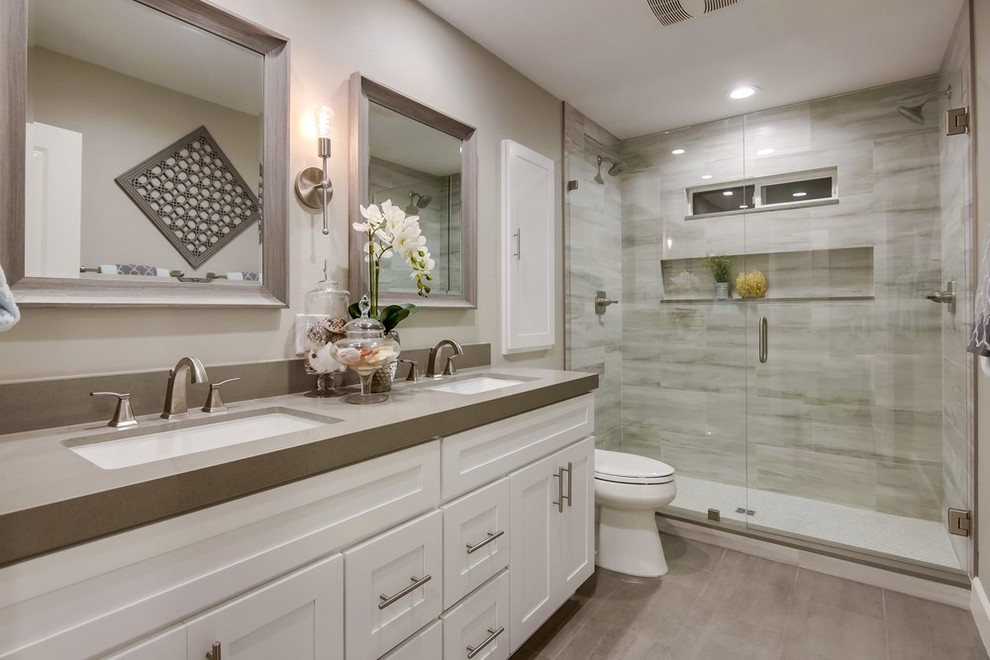 Idée de décoration pour une salle de bain design avec un placard à porte shaker, des portes de placard blanches, un carrelage gris, un mur gris, un lavabo encastré, un sol gris, une cabine de douche à porte battante et un plan de toilette gris.
